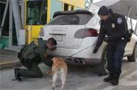 A Border Patrol agent and a CBP officer train a CBP canine to detect contraband in or around a vehicle A Border Patrol agent and a CBP officer train a CBP canine to detect contraband in or around a vehicle